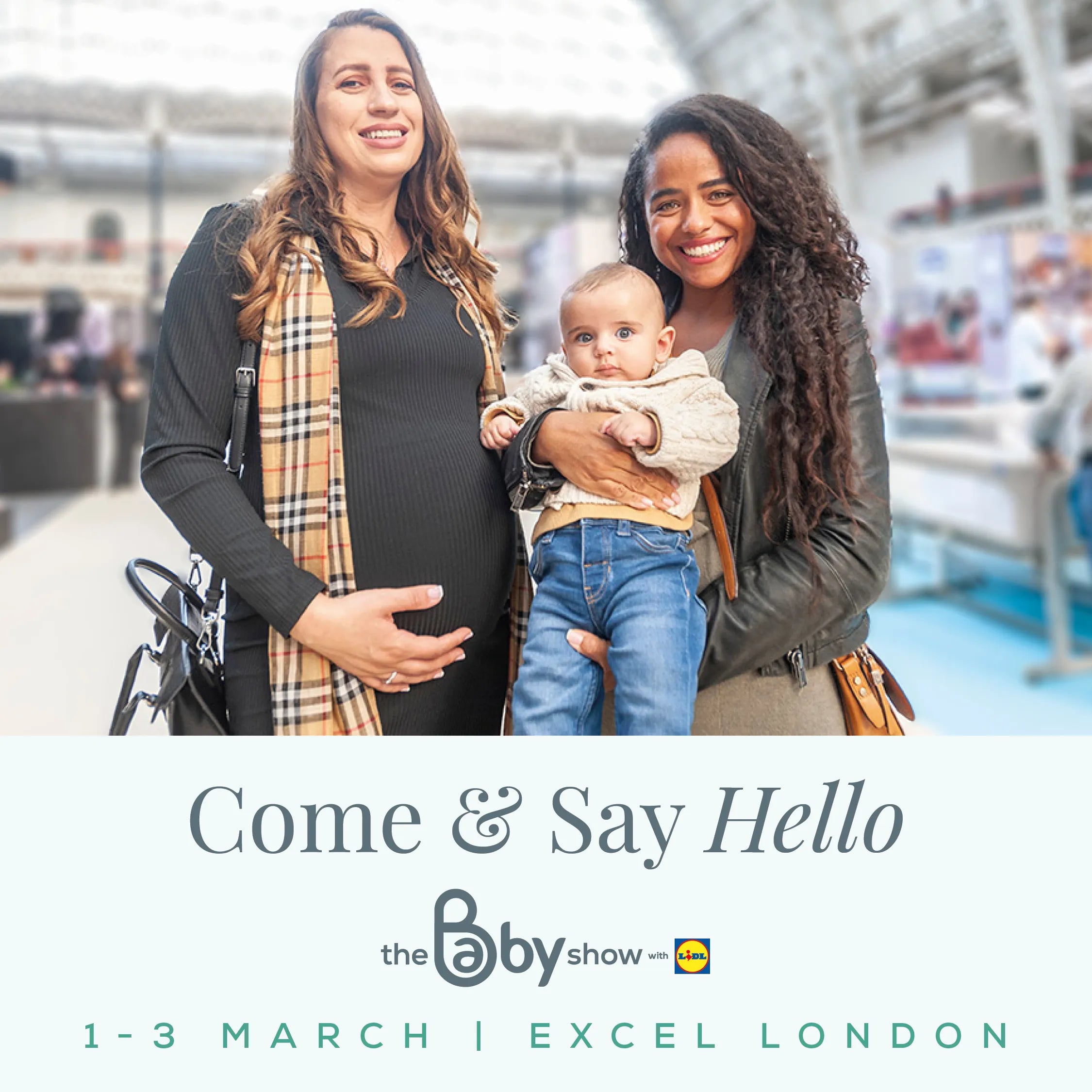 Pregnant woman and friend holding a baby at The Baby Show, Excel London.