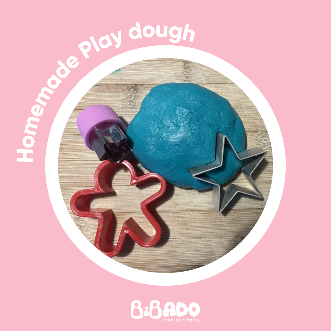 Vibrant blue homemade play dough with star and gingerbread man cutters on a wooden board.
