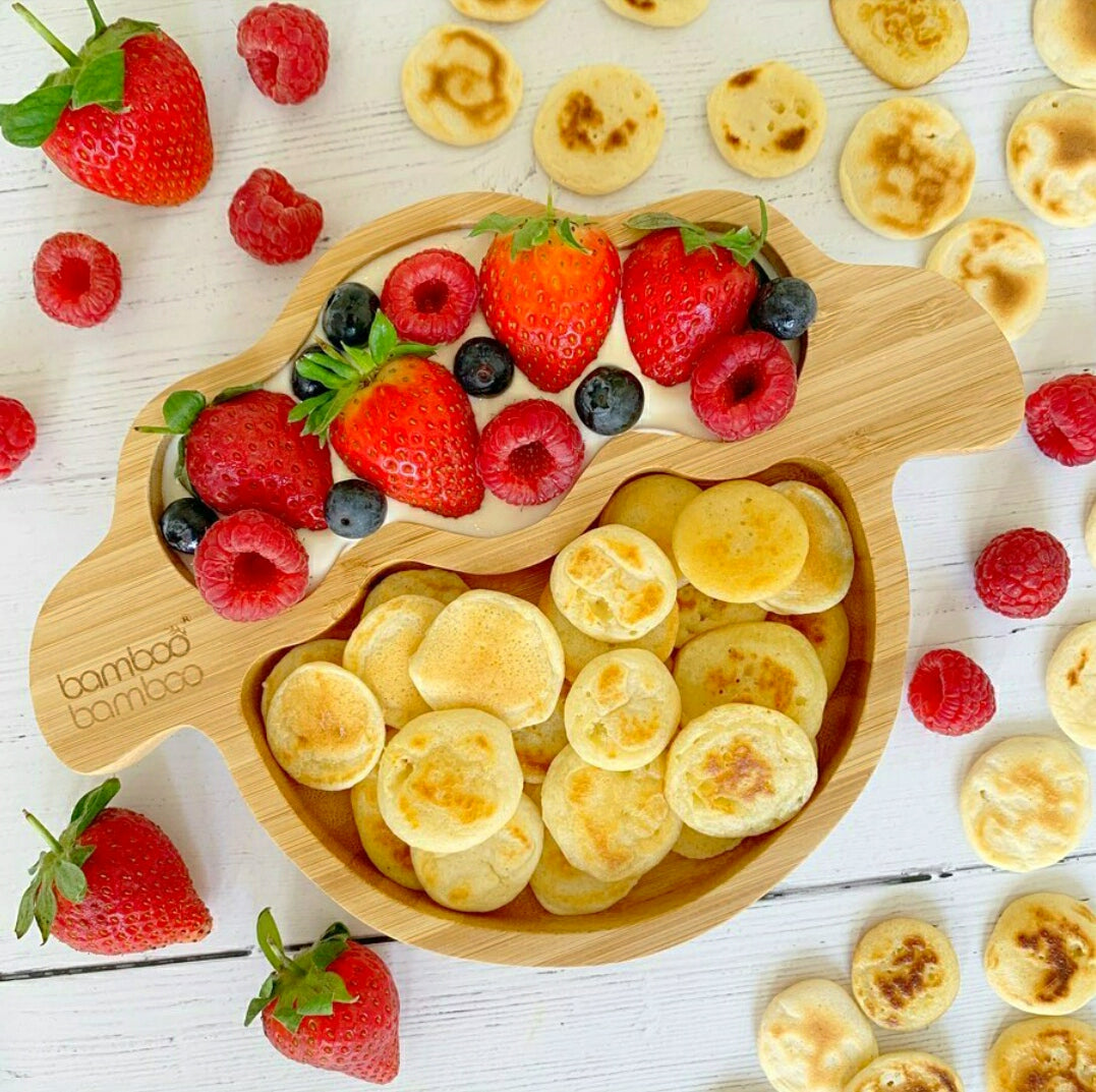 Miniature pancakes with strawberries, raspberries, and blueberries in a bamboo bowl.