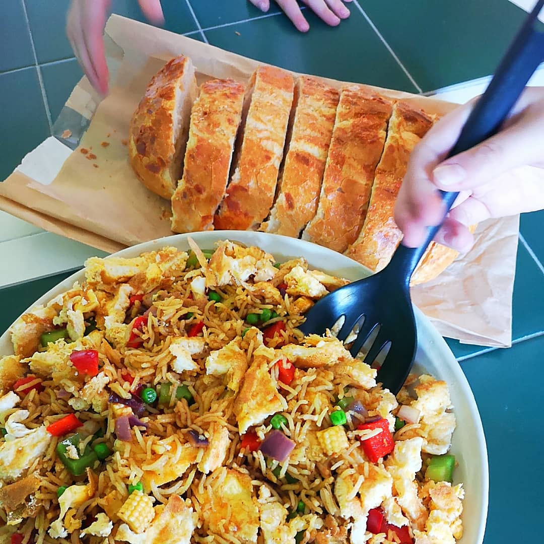 Colourful fried rice with vegetables and egg, served with sliced crusty bread.