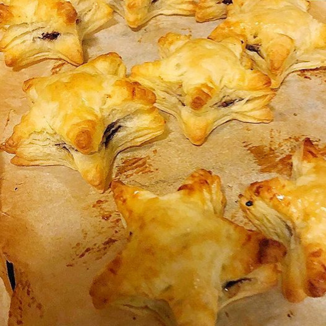 Golden, star-shaped baby-friendly mince pies with flaky puff pastry on a baking tray.