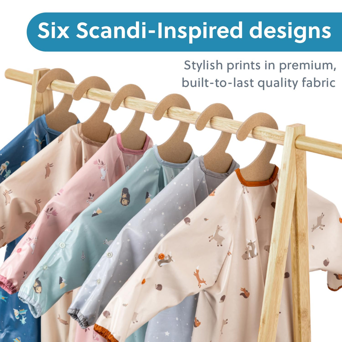Six long-sleeved weaning bibs in various Scandi-inspired prints, hanging on a wooden rack. - Product image