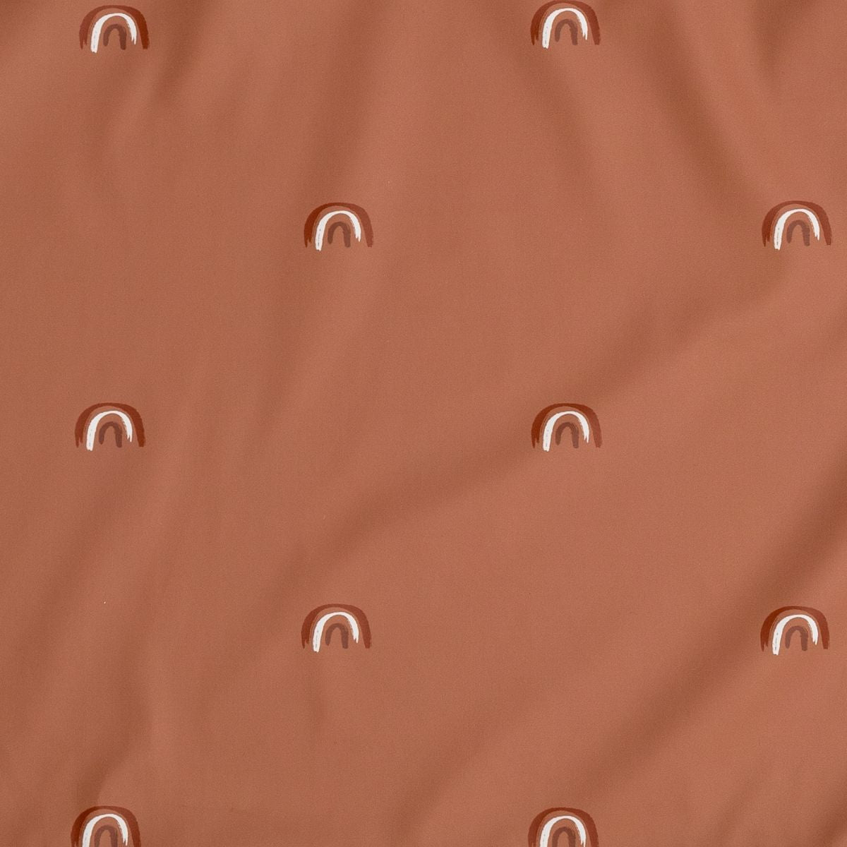Close-up of a rust-colored long-sleeve weaning bib with a pattern of small, white and brown hand-drawn rainbows. - Product image