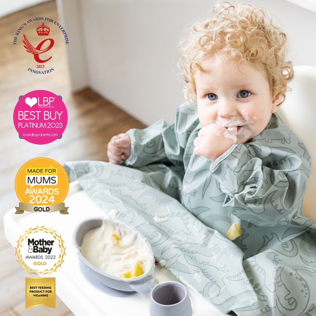 Toddler in a grey dinosaur-print weaning bib, eating from a grey suction bowl with a matching cup. - Product image