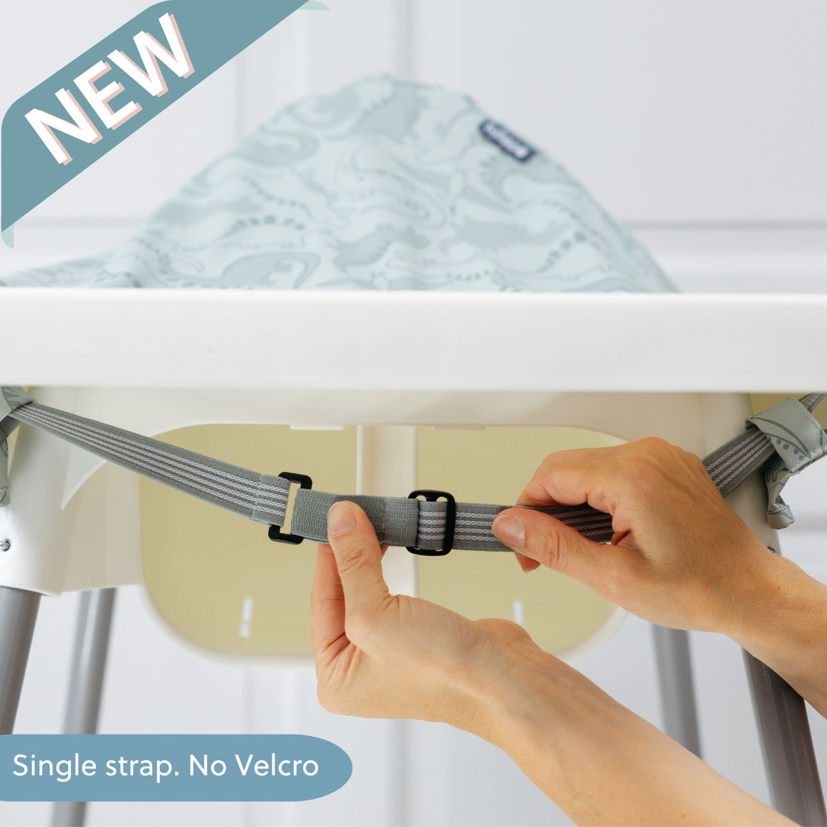Hands adjusting a grey striped bib strap with a black buckle on a white high chair, a light green patterned bib visible. - Product image