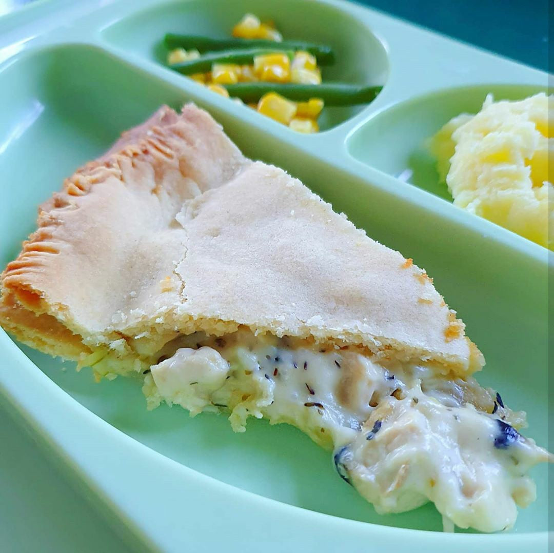 Slice of chicken and mushroom pie with creamy filling, served with mashed potato, green beans, and sweetcorn.