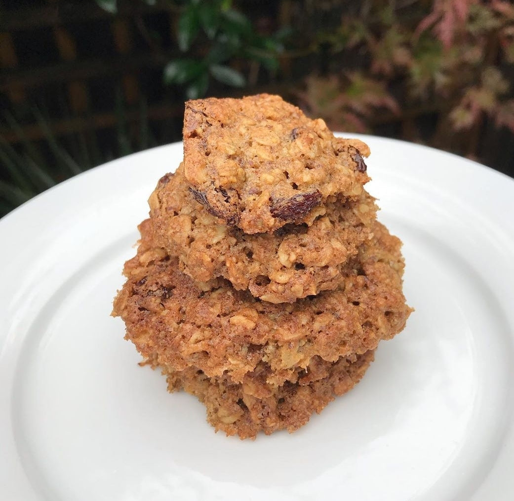 Stack of three golden brown oat and raisin cookies on a white plate.