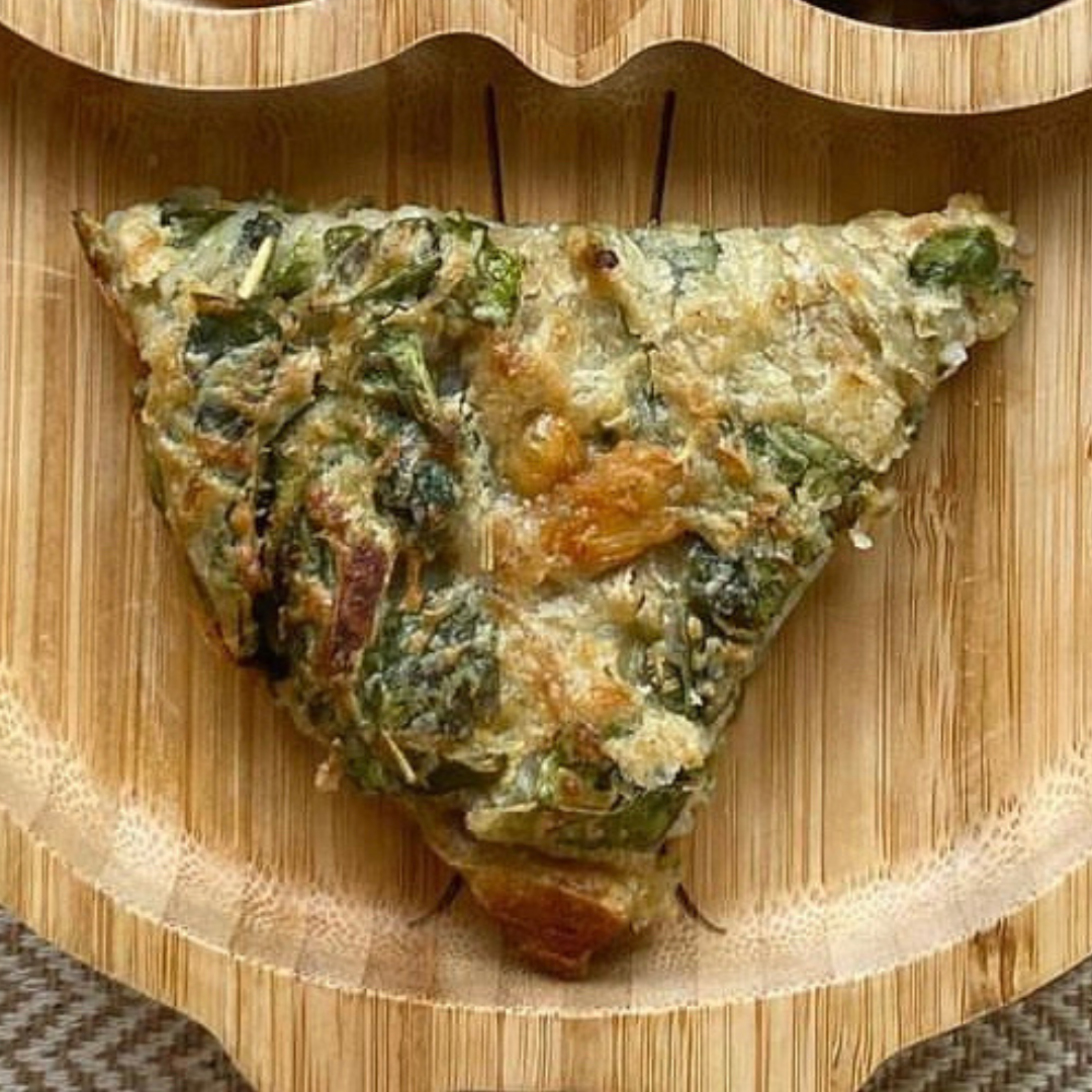 Golden-brown, triangular egg-free cheesy potato cake with green herbs on a wooden plate.