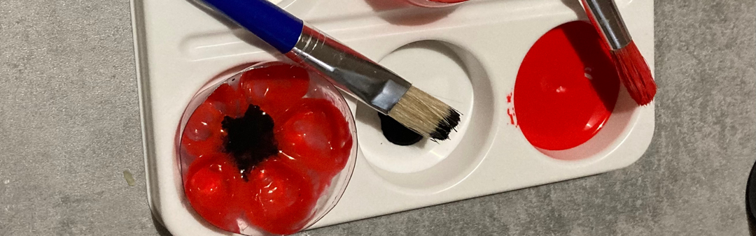 Crafting poppies: red and black paint in a white palette with paintbrushes.