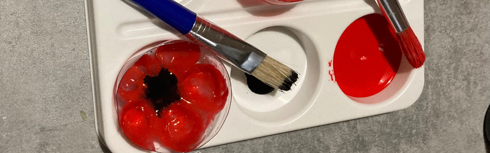 Crafting poppies: red and black paint in a white palette with paintbrushes.