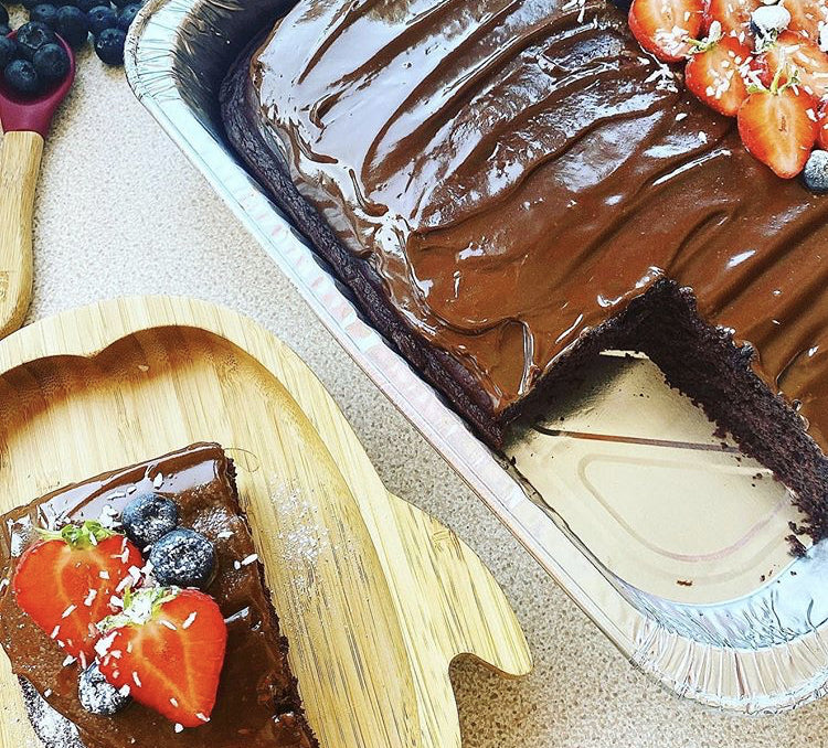 Rich chocolate sheet cake with glossy fudge icing, topped with fresh strawberries and blueberries.