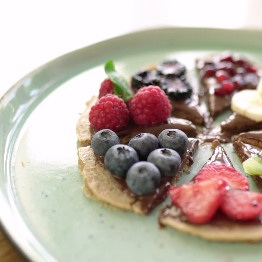 Sweet pancake pizzas with chocolate spread, raspberries, blueberries, and other fruits.