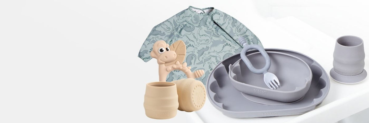 Spring bundles featuring neutral-toned silicone baby feeding sets, dinosaur bibs, and giraffe swaddles.