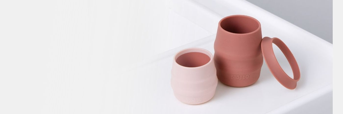 Stacked Bibado bamboo bowls and pastel silicone open cups on a white surface.