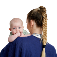 Woman using a light grey bamboo muslin Poppit On feeding cover, looking down at a baby (unseen). - Product image
