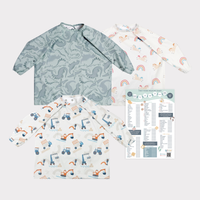 Three long-sleeve coverall weaning bibs: green dinosaur, white unicorn rainbow, and white construction vehicles. Includes a weaning chart.
