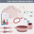 Pink silicone feeding set with bibs, utensils, bowl, cup, and "Baby-Led Weaning Made Easy" book.