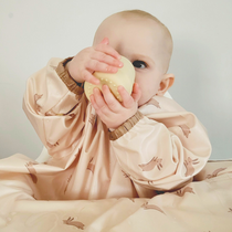 Baby in a peach bunny-print long-sleeved bib, holding a yellow textured ball.