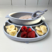 Light blue silicone baby plate with banana slices, raspberries, and a bowl of purée with a spoon.