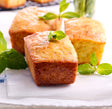 Golden brown mini loaves, garnished with fresh mint leaves, on white paper.