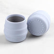 Two light blue Bibado Sippit silicone open training cups, one upright, one on its side showing the textured base.