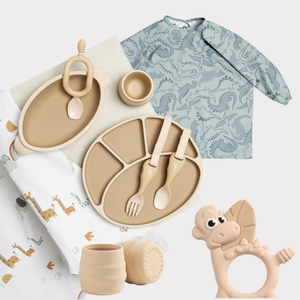 Baby feeding essentials: beige silicone plates, cups, cutlery, a dinosaur-patterned bib, and a dinosaur teether.