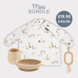 White long-sleeve baby bib with safari animals, beige silicone suction bowl, cup, and teether.