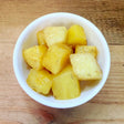 Small white bowl filled with golden roasted potato chunks, lightly seasoned with black pepper.