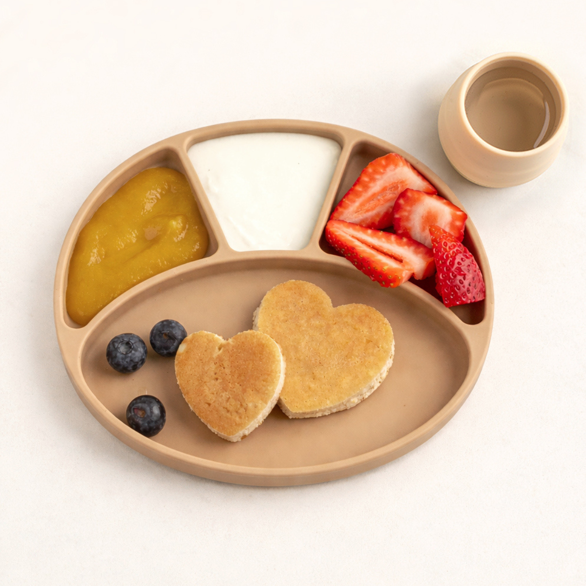Children's plate with heart-shaped pancakes, fruit, and a small cup on a white background - Product image